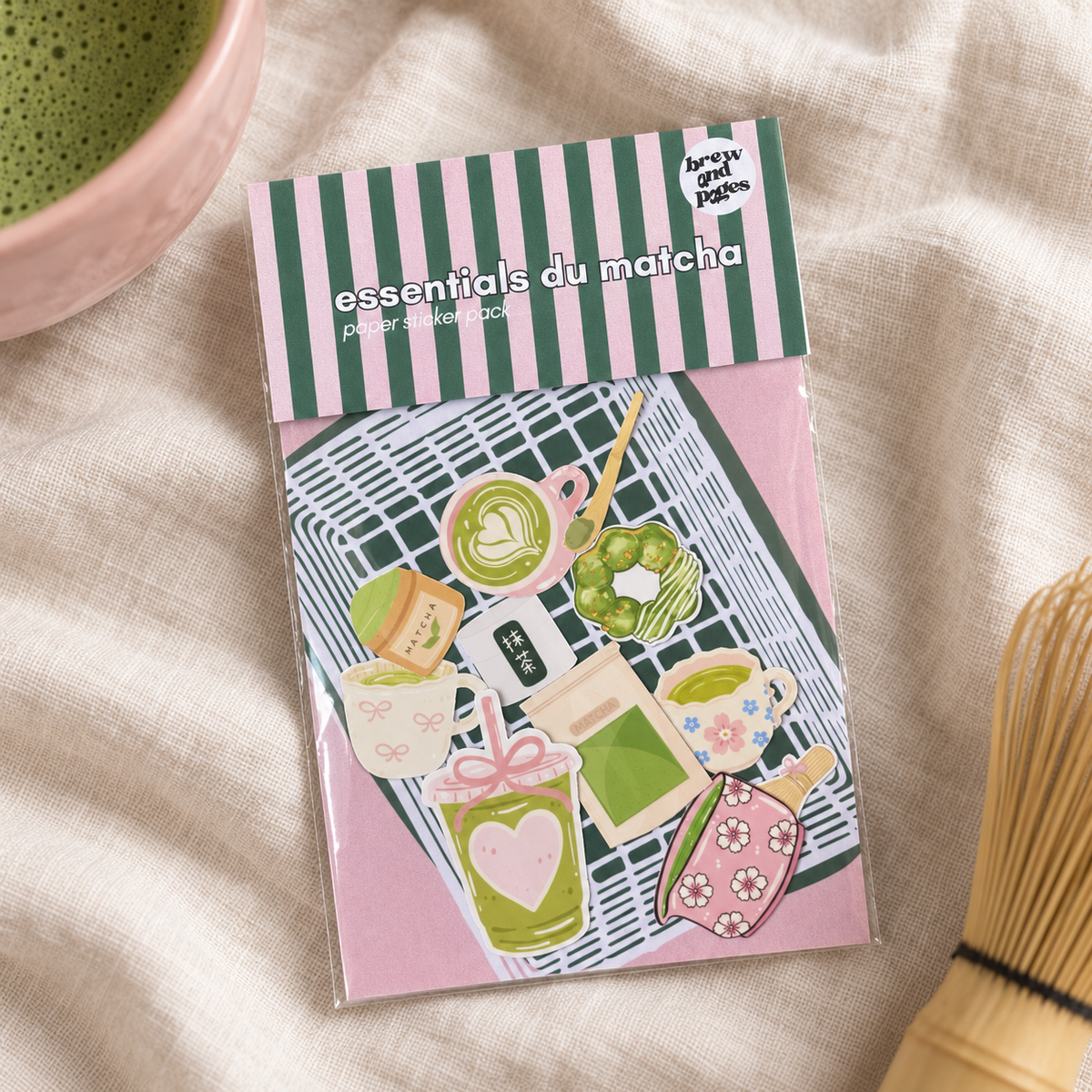 Matcha paper sticker pack styled with a ceramic matcha bowl and bamboo whisk on cream linen.